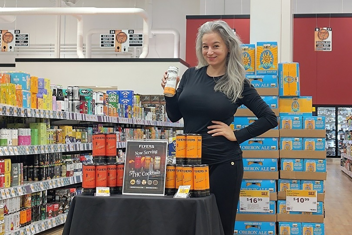 Brand ambassador holding a Flyers THC cocktail can at an in-store product sampling display at Binny's Beverage Depot